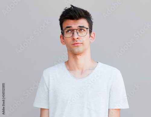 Handsome man rolls eyes on grey background