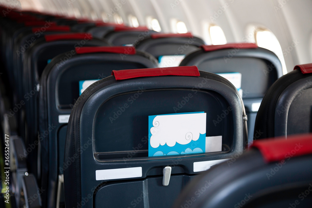 Fototapeta premium Airplane instruction, layout with place for text. Advertising brochure. Empty cabin of the plane. Soft seats for passengers, portholes. Inside a passenger plane. A seat on the plane. Copy space.