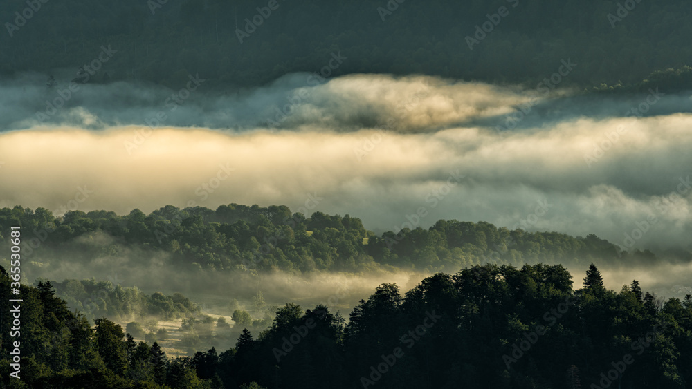A hazy sunrise in the mountains. Mountains silhouettes and fog in the valleys. Photo from Polonina Wetlinska. Bieszczady National Park. Carpathians. Poland. A hazy sunrise in the mountains. Mountains silhouettes and fog in the valleys. Photo from Polonina Wetlinska. Bieszczady National Park. Carpathians. Poland.