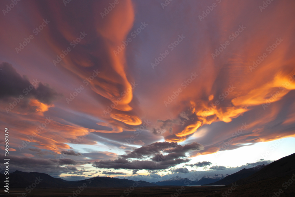 Cielo dramático con nubes lenticulares anaranjadas al atardecer en Patagonia.