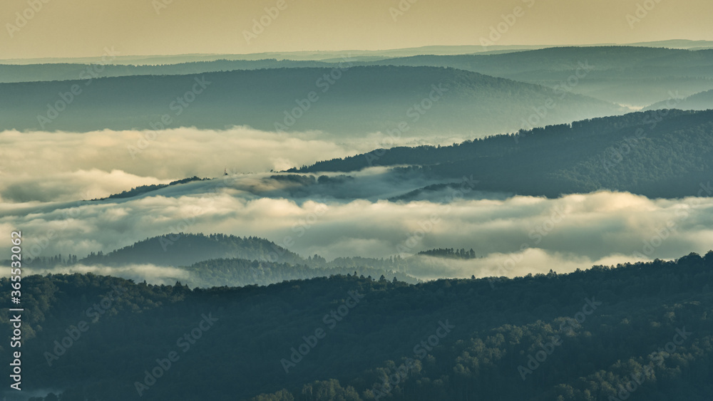Fototapeta premium A hazy sunrise in the mountains. Mountains silhouettes and fog in the valleys. Photo from Polonina Wetlinska. Bieszczady National Park. Carpathians. Poland.