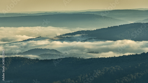 Fototapeta Naklejka Na Ścianę i Meble -  A hazy sunrise in the mountains. Mountains silhouettes and fog in the valleys. Photo from Polonina Wetlinska. Bieszczady National Park. Carpathians. Poland.