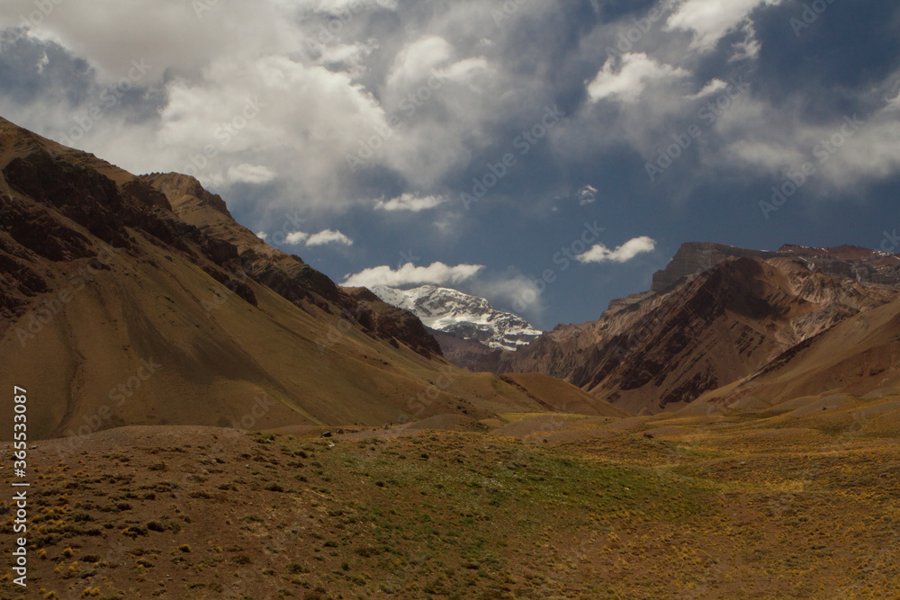 Panorama view of the mountains valley and yellow meadow in autumn. Mountain Aconcagua, highest peak in America, in the background. 