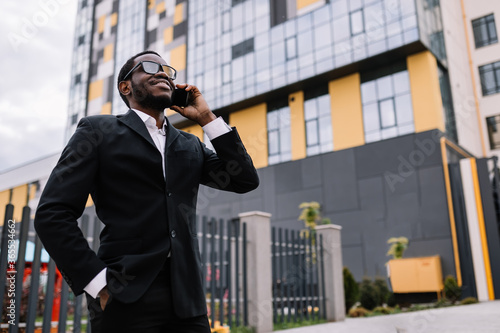 afroamerican man talking on the phone near modern office center
