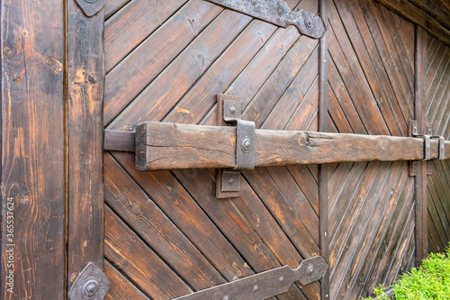 old wooden log gates with forged hinges, loops and rivets