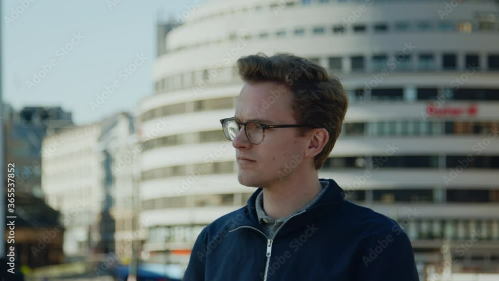 Modern caucasian with glasses looking up from phone commuting and navigating European downtown financial district pondering a 5g technological lifestyle Modern caucasian with glasses looking up from phone commuting and navigating European downtown financial district pondering a 5g technological lifestyle