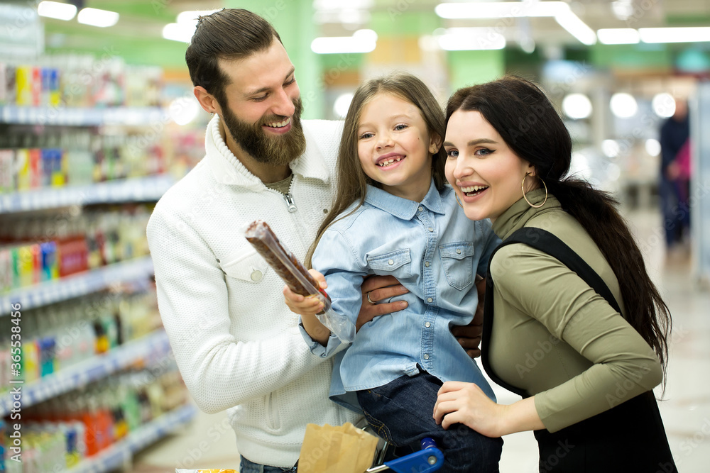 Family with shopping cart with food visiting supermarket