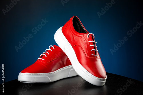 mens red leather shoes with white soles on blue background