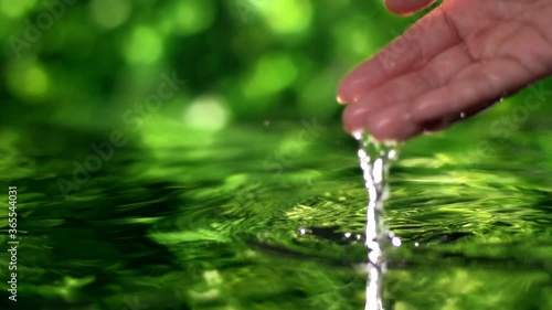close up woman hand gently touches the surface of the water photo