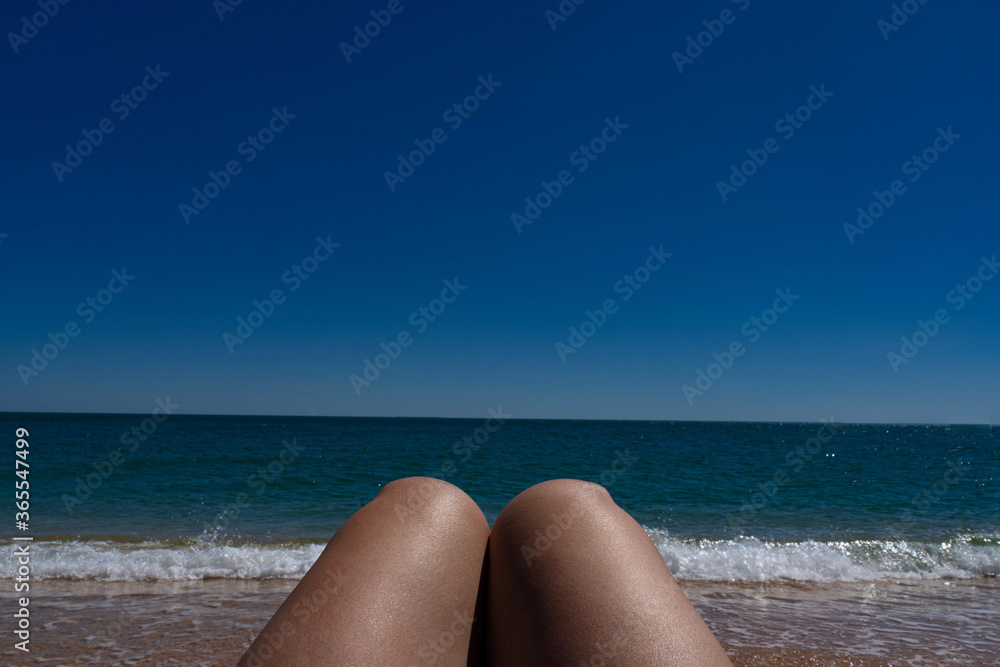 tanned female legs against the background of the azure sea tanned female legs against the background of the azure sea