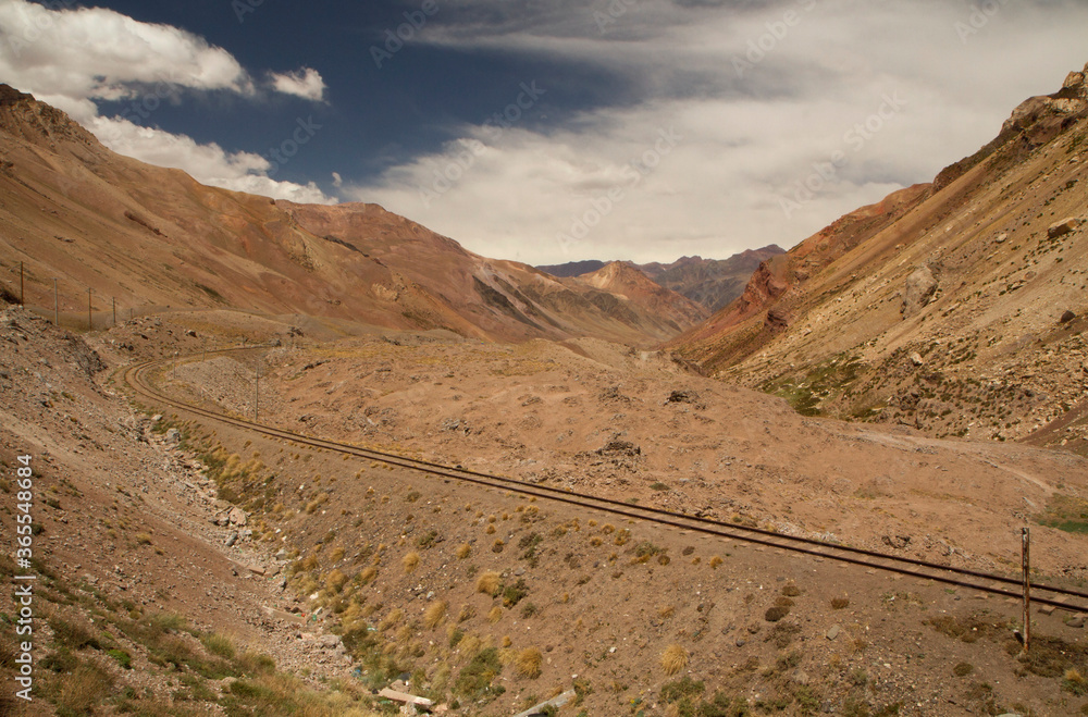 Rural railroad. View of the train railway across the arid desert valley and red rocky mountains. 