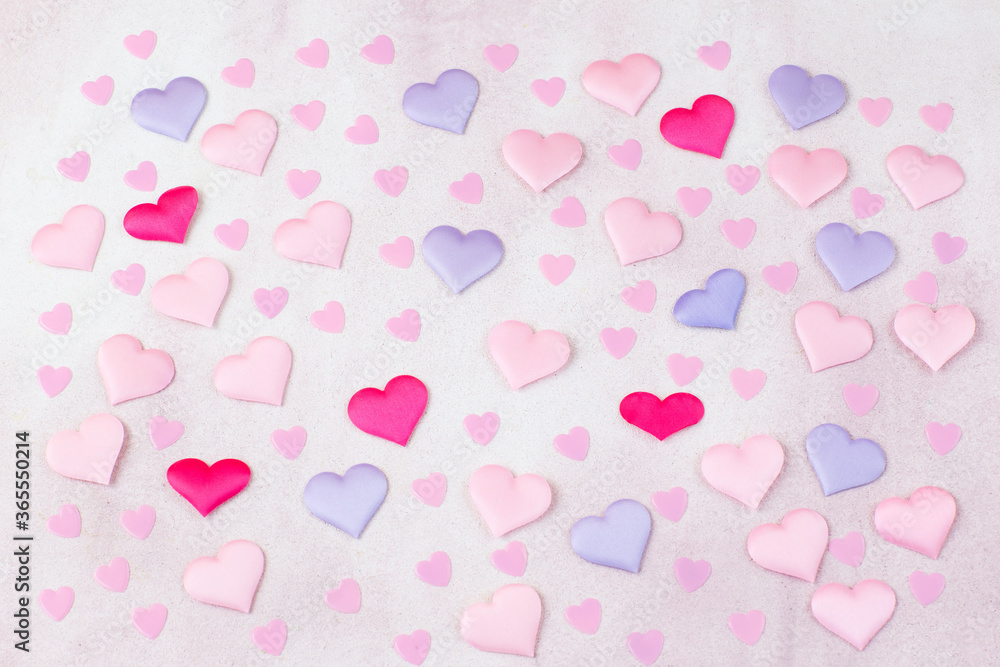 on a pink background colored hearts from satin