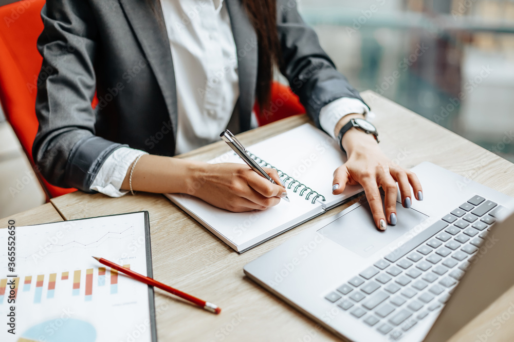 Girl works on a laptop in the workplace. Successful business woman creates a startup and makes decisions. Girl works on a laptop in the workplace. Successful business woman creates a startup and makes decisions.