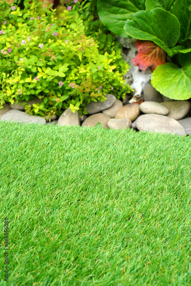 Soft artificial grass in the yard. Comfort at home. Vertical.