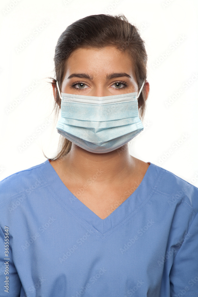 Young Woman Wearing Medical Scrubs and a Surgical Mask Young Woman Wearing Medical Scrubs and a Surgical Mask