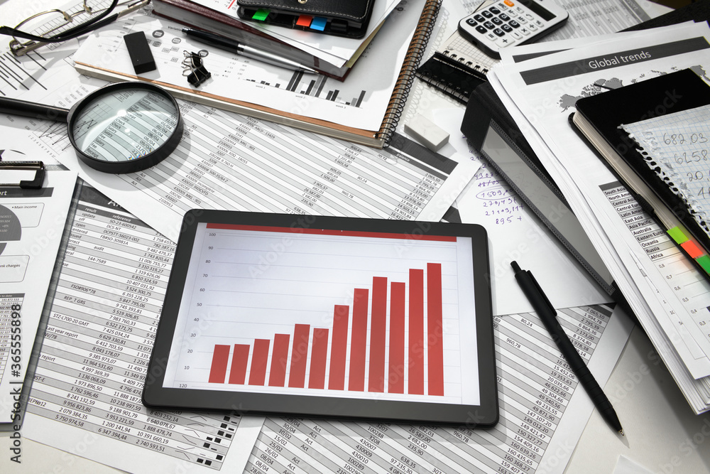 business office desk closeup - tablet computer with tables and graphs on the screen, financial reports, analysis and accounting, set of documents for bookkeeping business office desk closeup - tablet computer with tables and graphs on the screen, financial reports, analysis and accounting, set of documents for bookkeeping