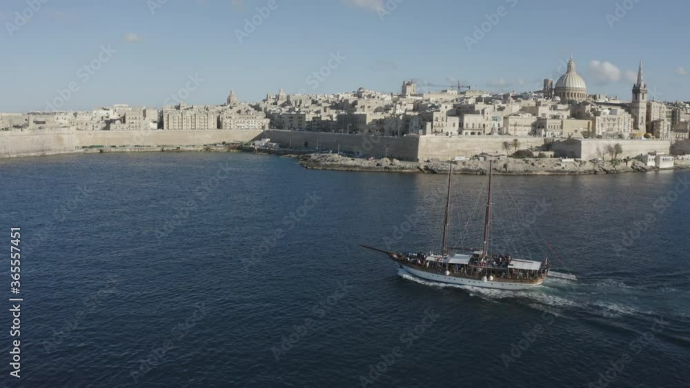 Scenic drone panorama of boat sailing away from harbor with historic city in background Scenic drone panorama of boat sailing away from harbor with historic city in background