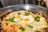 Fresh breakfast fried eggs in pita bread, in a large frying pan, closeup, shallow depth of field, selective focus. Fast breakfast concept