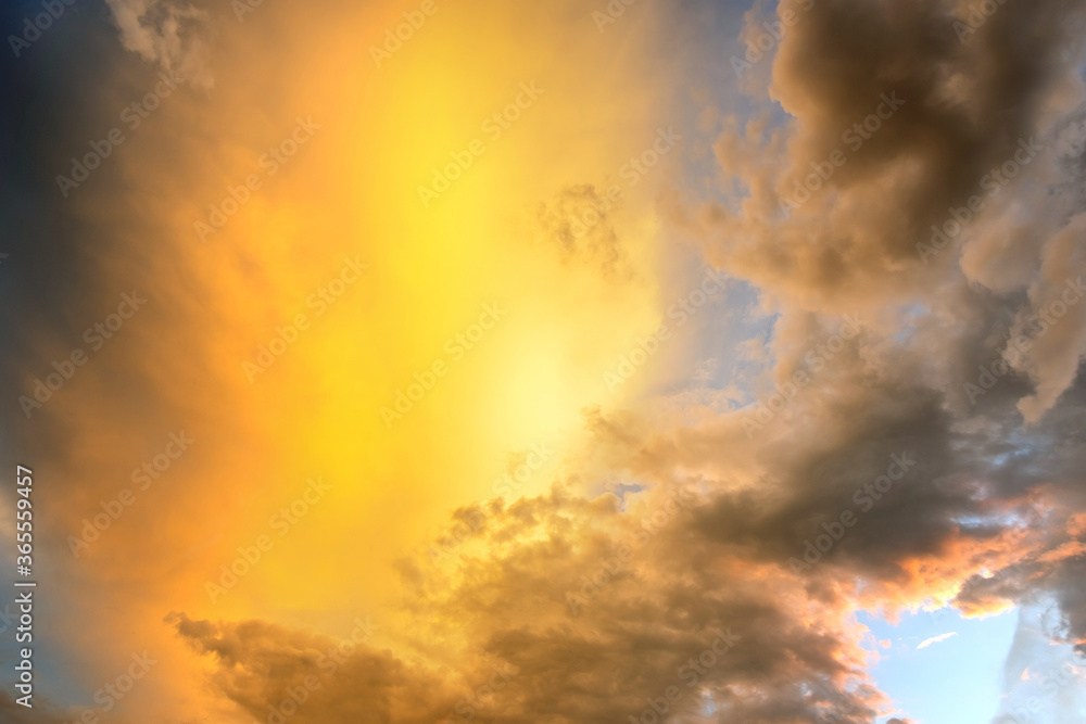 Dramatic sunset sky landscape with puffy clouds lit by orange setting sun and blue heavens. Dramatic sunset sky landscape with puffy clouds lit by orange setting sun and blue heavens.