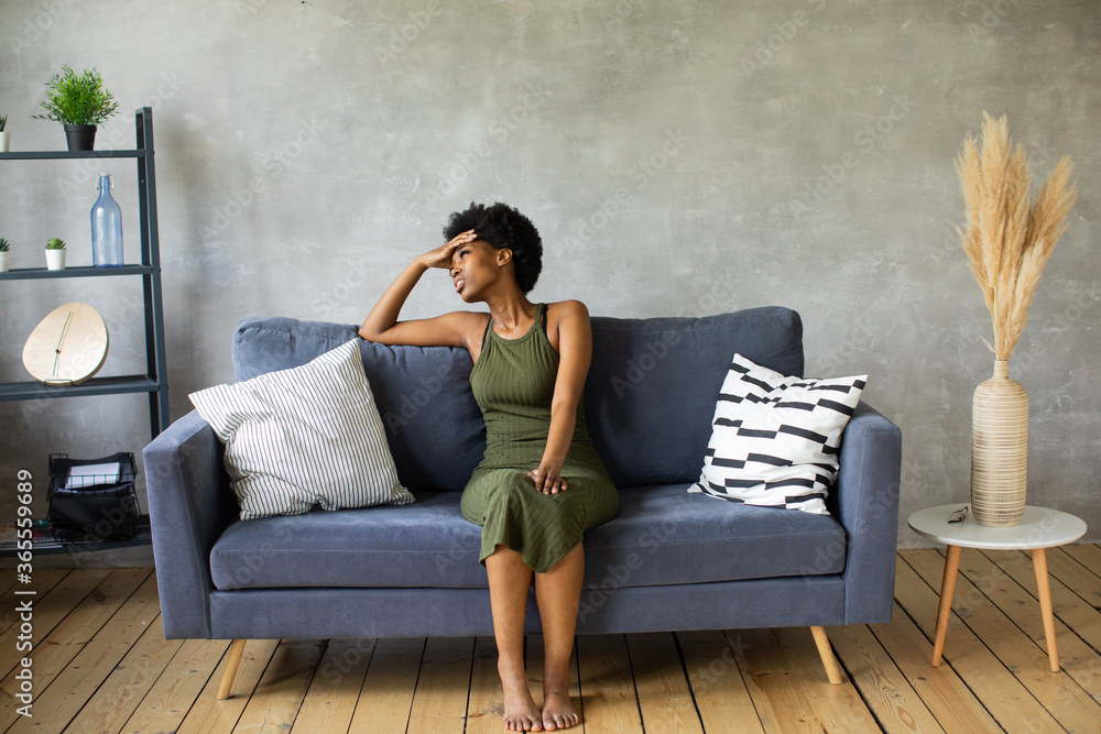 Unhappy African American woman sit on the sofa, the girl is very upset sitting on the couch of her apartment. Unhappy African American woman sit on the sofa, the girl is very upset sitting on the couch of her apartment.