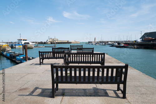 Wooden benches in the Royal Harbour, Ramsgate, looking out towards the lighthouse and an end of pier restaurant © Christine Bird