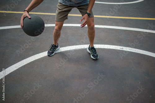 guy in a gray t-shirt and shorts with a dark basketball ball on a basketball court