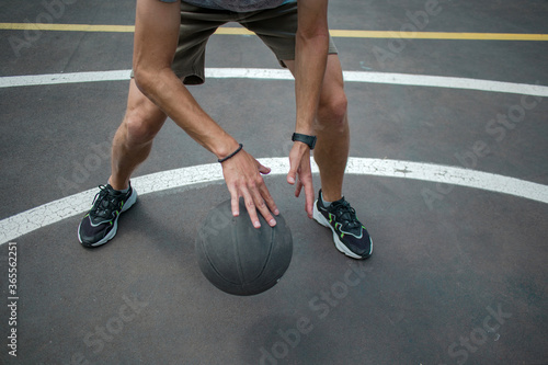 guy in a gray t-shirt and shorts with a dark basketball ball on a basketball court