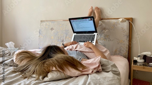woman working or learning from home with laptop and phone in the comfort of her bed due to covid-19 pandemic social distancing quarantine practices Work in isolation 
