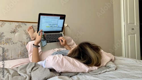 woman using laptop And phone working or learning from home due to covid-19 pandemic social distancing practices quarantine in the bed 