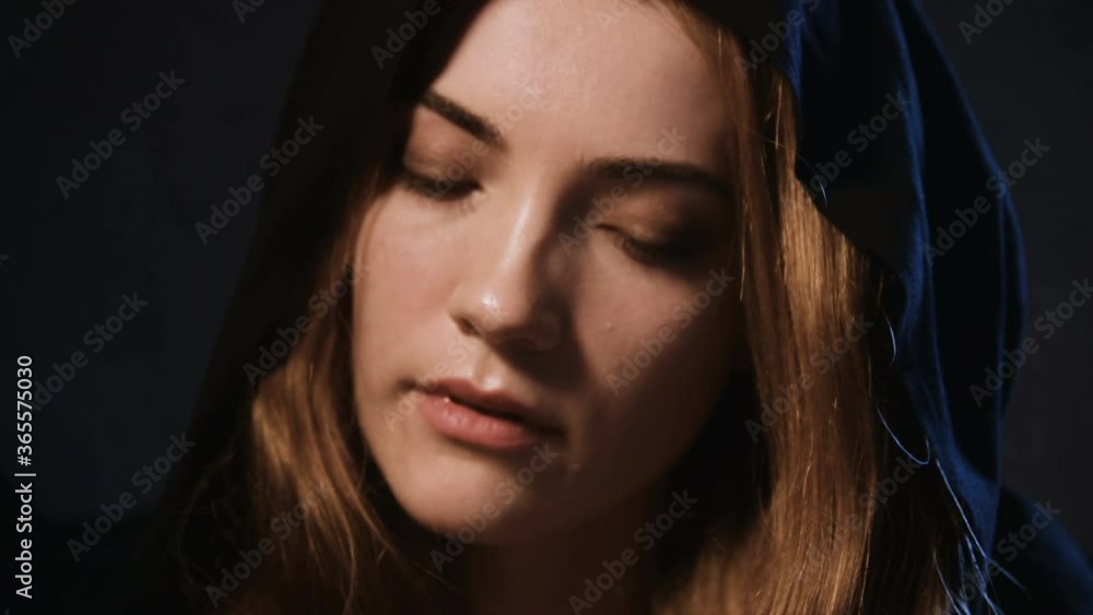 A close-up portrait of an attractive Caucasian woman in a black hood with blond hair playing the look enchanting and flirting. The concept of the magic of love and the holiday of Halloween A close-up portrait of an attractive Caucasian woman in a black hood with blond hair playing the look enchanting and flirting. The concept of the magic of love and the holiday of Halloween