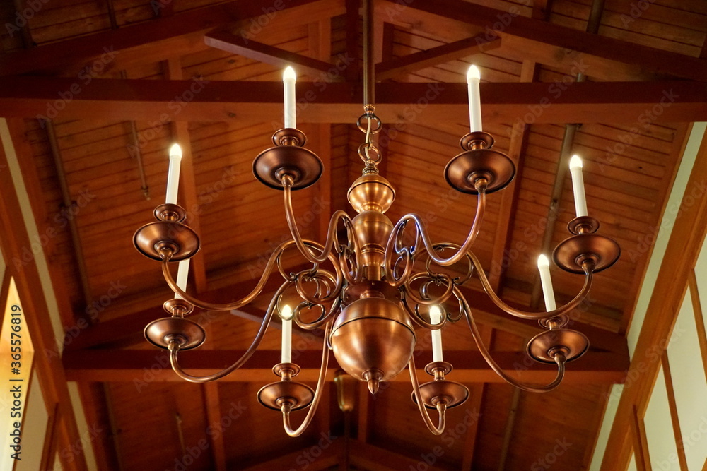 A large copper chandelier hanging on the wooden ceiling A large copper chandelier hanging on the wooden ceiling