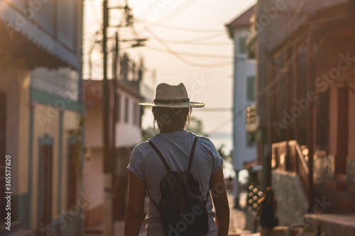
tourist woman walking down the street wearing a hat.