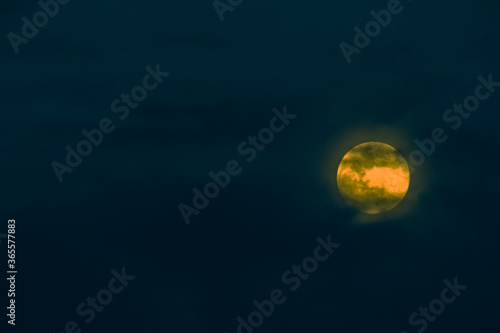 Bright yellow full moon behind clouds © aminkorea