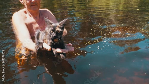 Man Holds Funny Kitten in His Arms above the Water in the River. Slow Motion photo