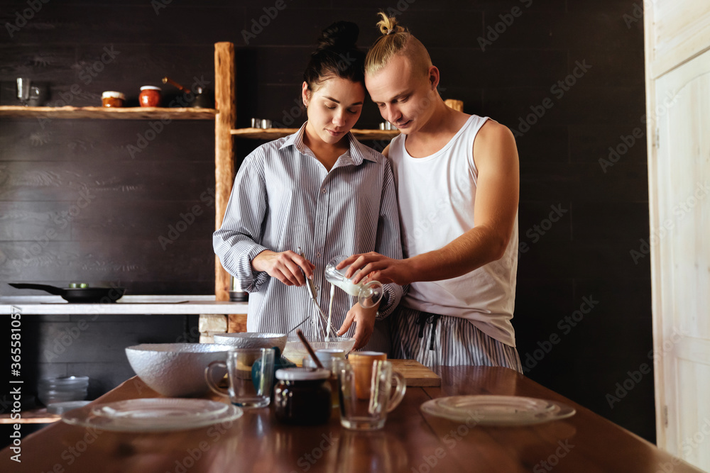 Beautiful young couple is smiling while cooking in kitchen at home Beautiful young couple is smiling while cooking in kitchen at home