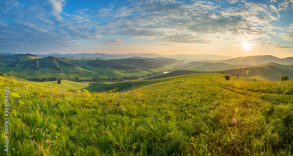 Scenic summer view. Setting sun, beautiful sky. Green hills and meadows.