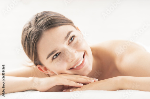 明るい雰囲気のエステサロンでマッサージを受ける若い女性