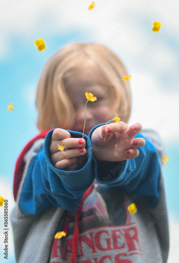 Little girl holding flowers while flowers rain