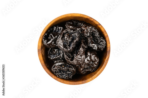 Top view of dried pitted prunes in wooden bowl on white background.