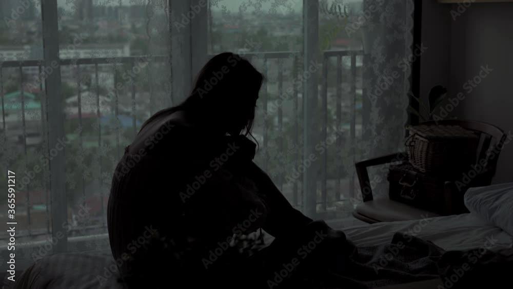 4K Silhouette of Depressed Young beautiful Asian woman sitting alone on the bed in apartment bedroom with crying. Loneliness sad girl think of grief trouble. Negative emotion and mental health concept 4K Silhouette of Depressed Young beautiful Asian woman sitting alone on the bed in apartment bedroom with crying. Loneliness sad girl think of grief trouble. Negative emotion and mental health concept