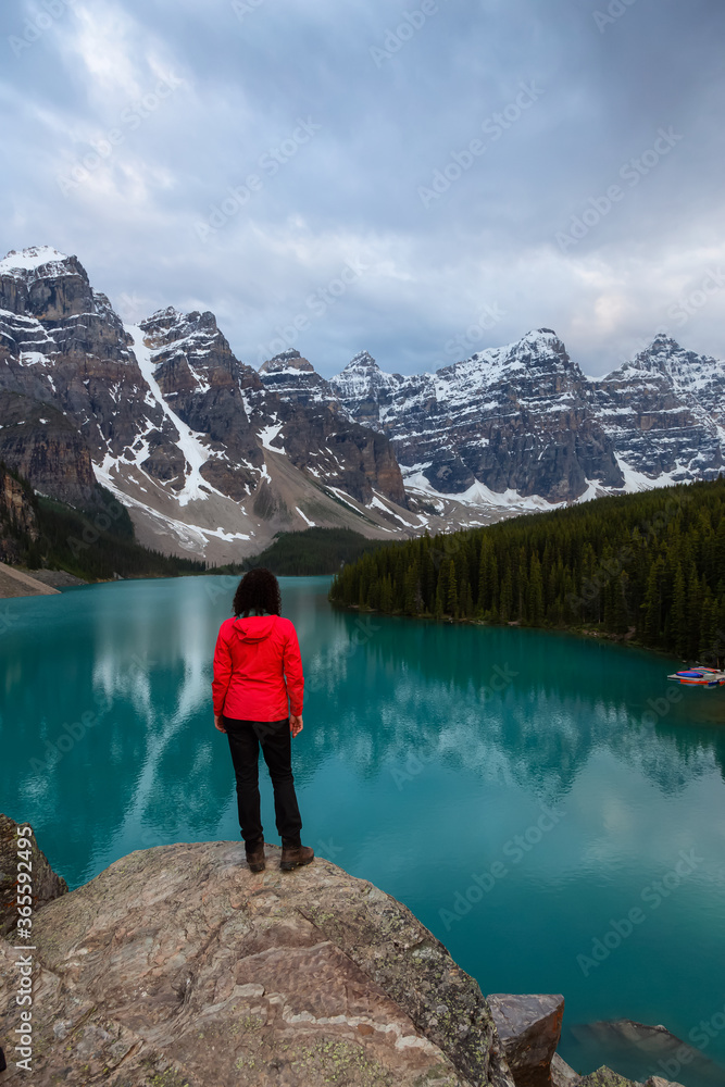 Adventure Girl is looking at a beautiful Iconic Canadian Rocky Mountain Landscape during sunset. Taken at Moraine Lake, Banff National Park, Alberta, Canada.