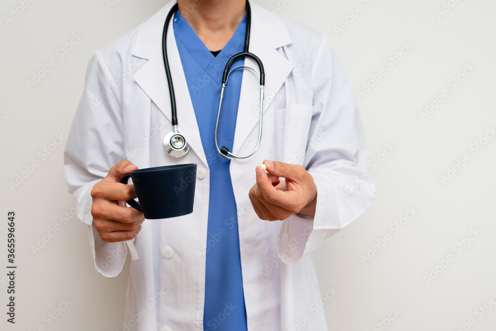 薬を飲もうとする白衣を着た男性医師 薬を飲もうとする白衣を着た男性医師