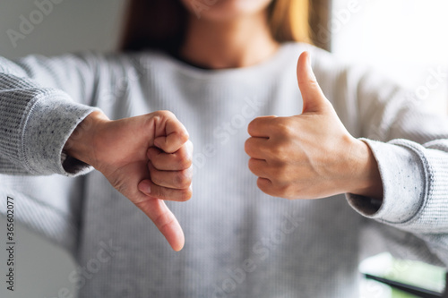 Closeup image of a woman making thumbs up and thumbs down hands sign photo