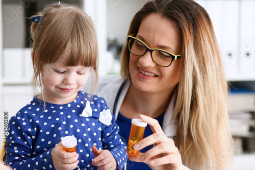 Beautiful smiling female doctor hold in arms pill bottle and offer it to child visitor closeup. Panacea or life save antidepressant from legal store prescribe vitamin medic aid for healthy lifestyle