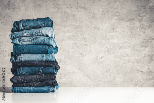 Stack of blue jeans on a gray background