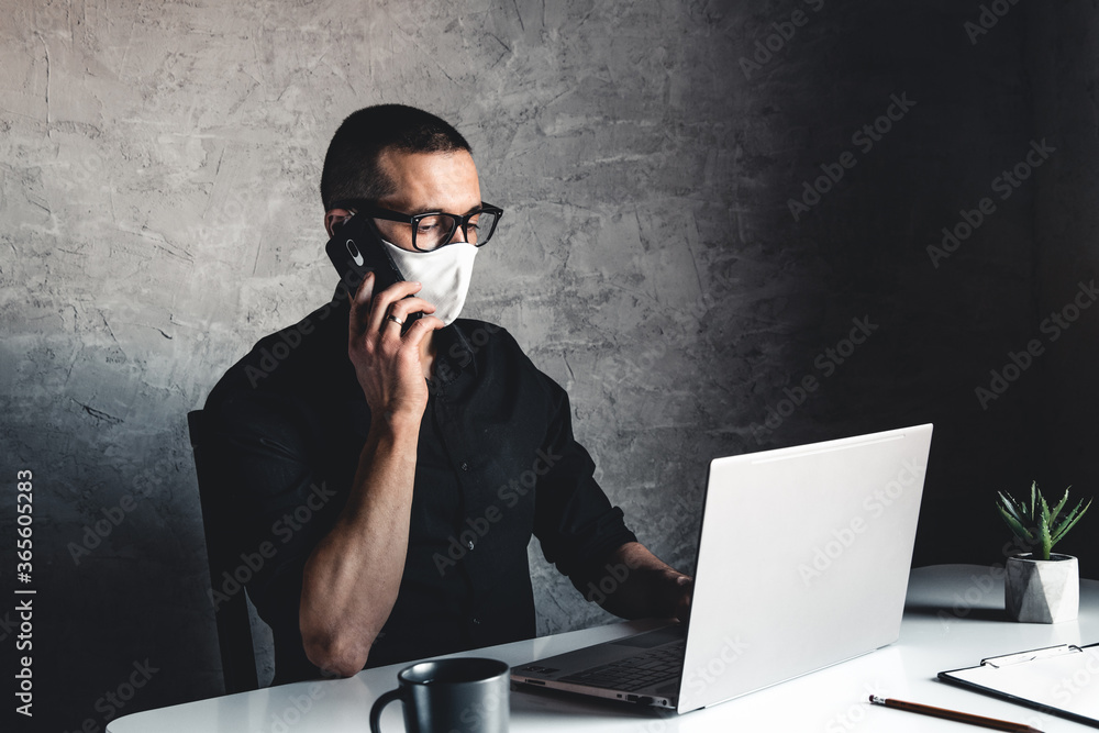 A masked man works at a computer. Pandemic, coronavirus, epidemic A masked man works at a computer. Pandemic, coronavirus, epidemic