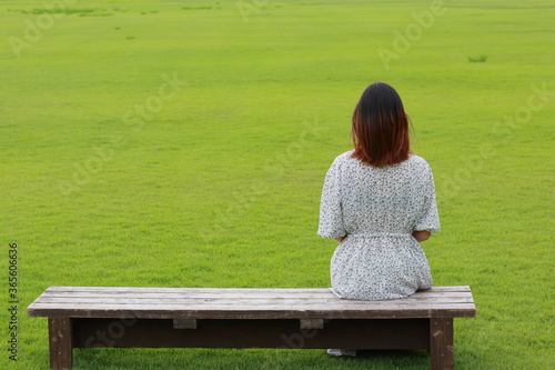 芝生でベンチに座る女性
