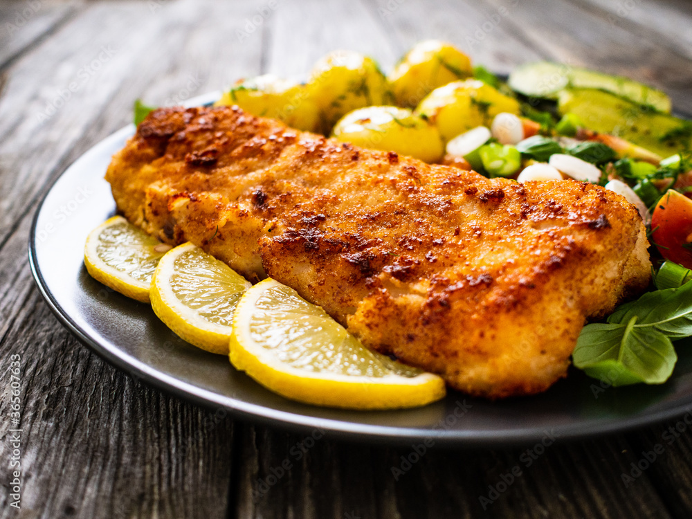 Fish dish - fried breaded cod fillet with vegetables on wooden table
Fish dish - fried breaded cod fillet with vegetables on wooden table
