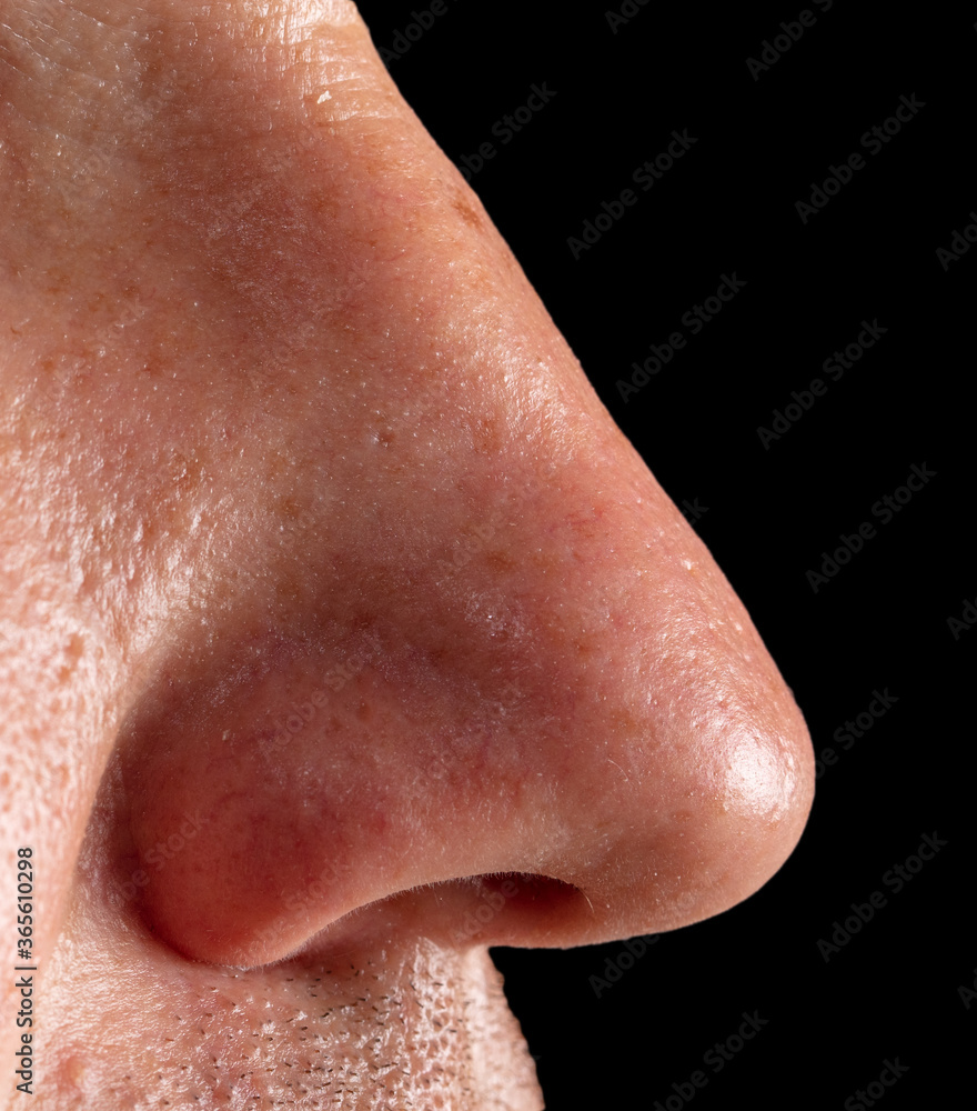 Fototapeta premium Close up of a man's nose isolated on a black background.