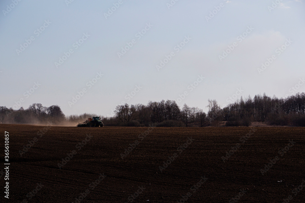 a large tractor with a seeder goes through the field.
